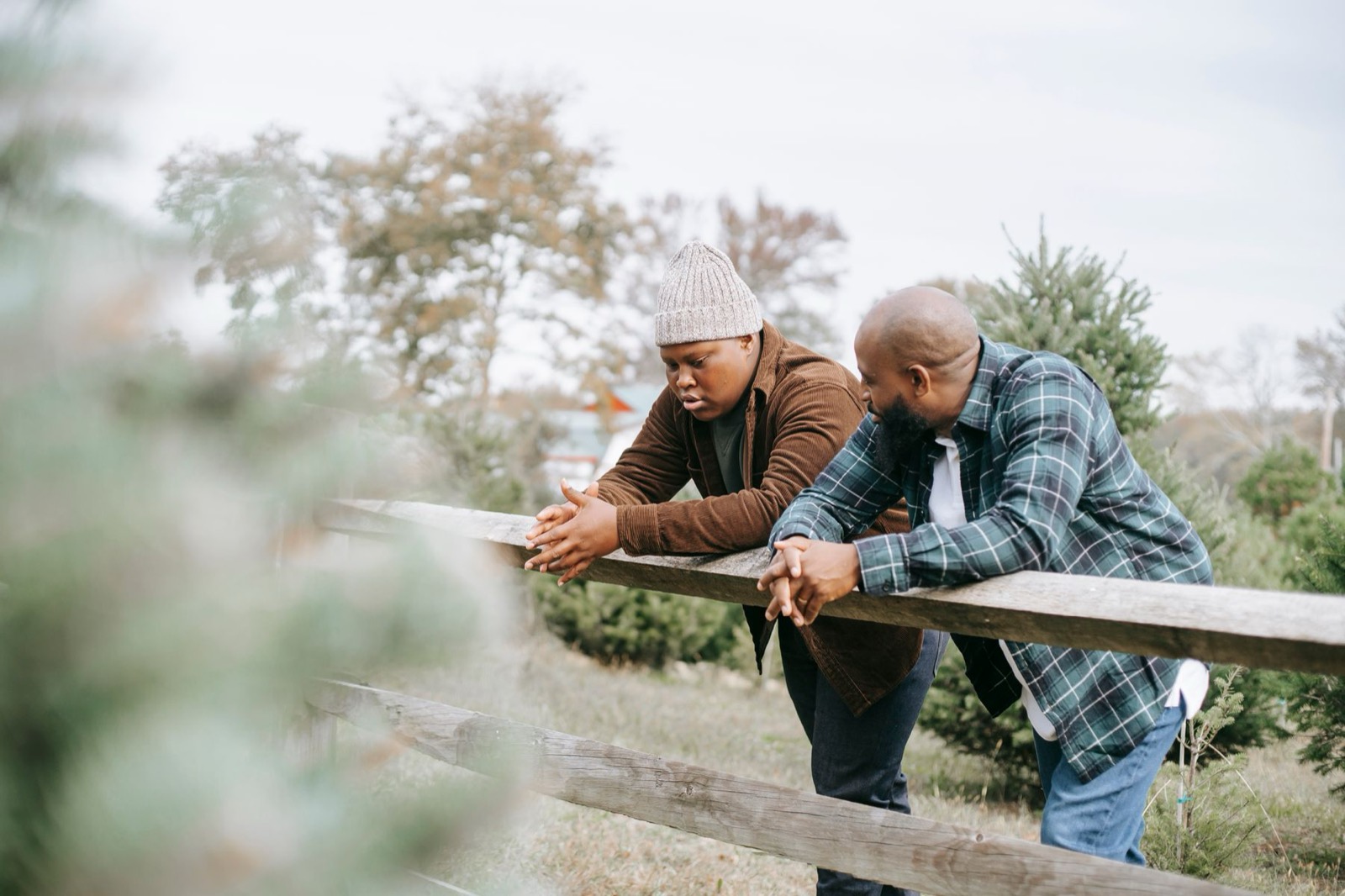 Two men talking at a wooden fence